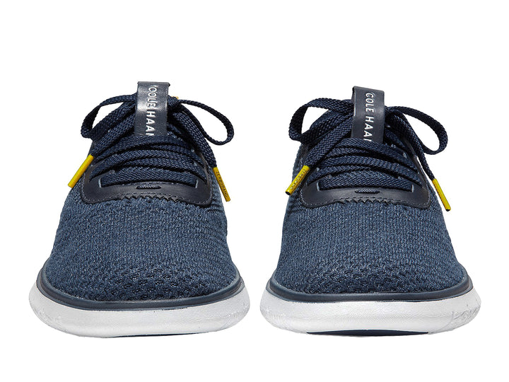 Tenis deportivos Cole Haan color azul marino con suela blanca y detalles en amarillo.