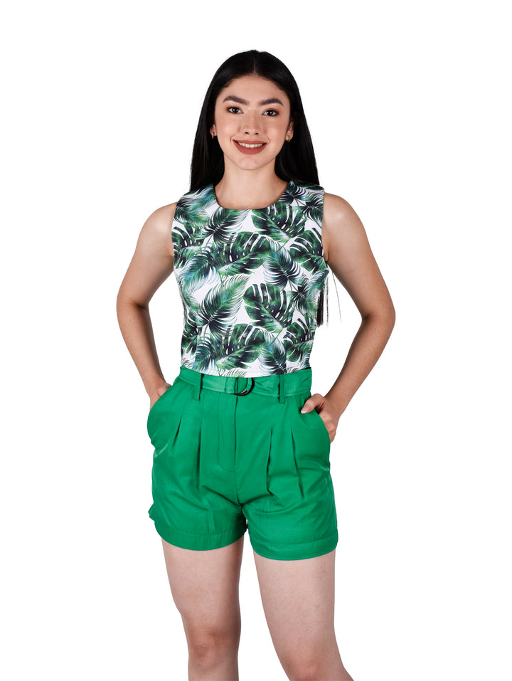 Mujer vistiendo un croptop blanco con estampado de hojas tropicales verdes y shorts verdes.
