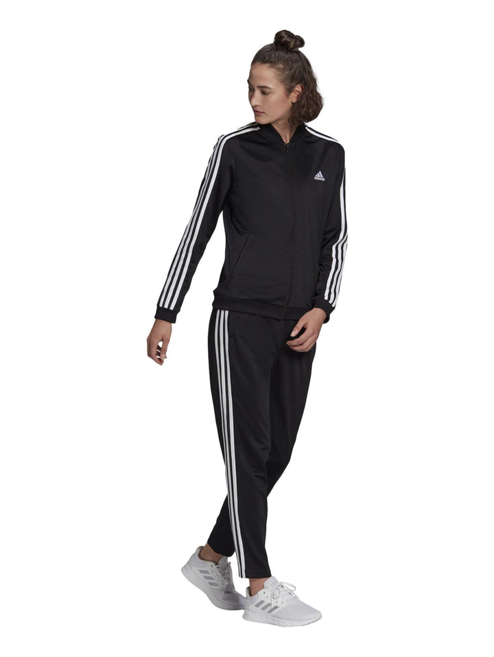 Conjunto deportivo Adidas negro para mujer con rayas blancas laterales y calzado blanco.