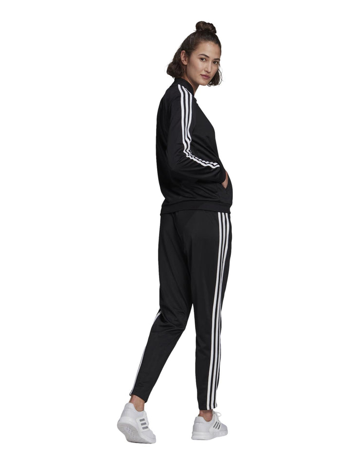 Conjunto deportivo Adidas negro para mujer con rayas blancas laterales y calzado blanco.