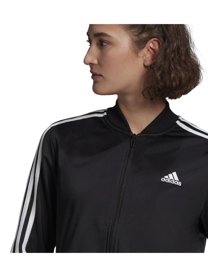 Conjunto deportivo Adidas negro para mujer con rayas blancas laterales y calzado blanco.