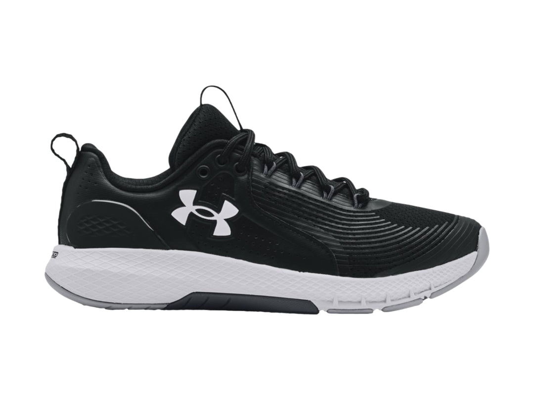 Tenis deportivos Under Armour Charged Commit TR 3 en color negro con suela blanca y logo lateral blanco.