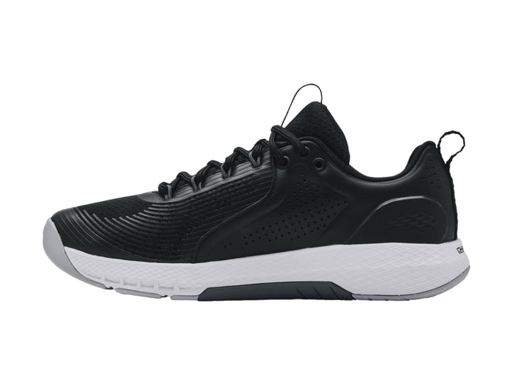 Tenis deportivos Under Armour Charged Commit TR 3 en color negro con suela blanca y logo lateral blanco.