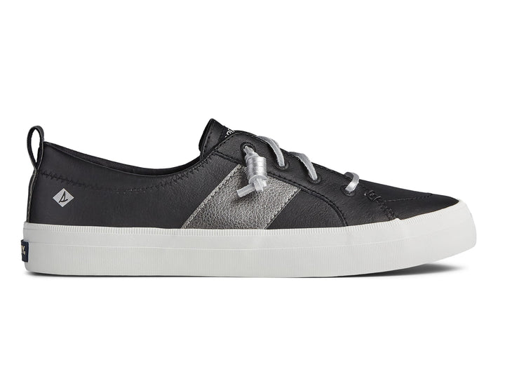 Zapato Sperry negro con franja plateada y suela blanca para mujer.