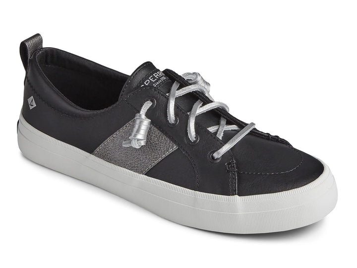 Zapato Sperry negro con franja plateada y suela blanca para mujer.