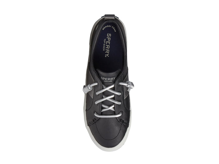 Zapato Sperry negro con franja plateada y suela blanca para mujer.
