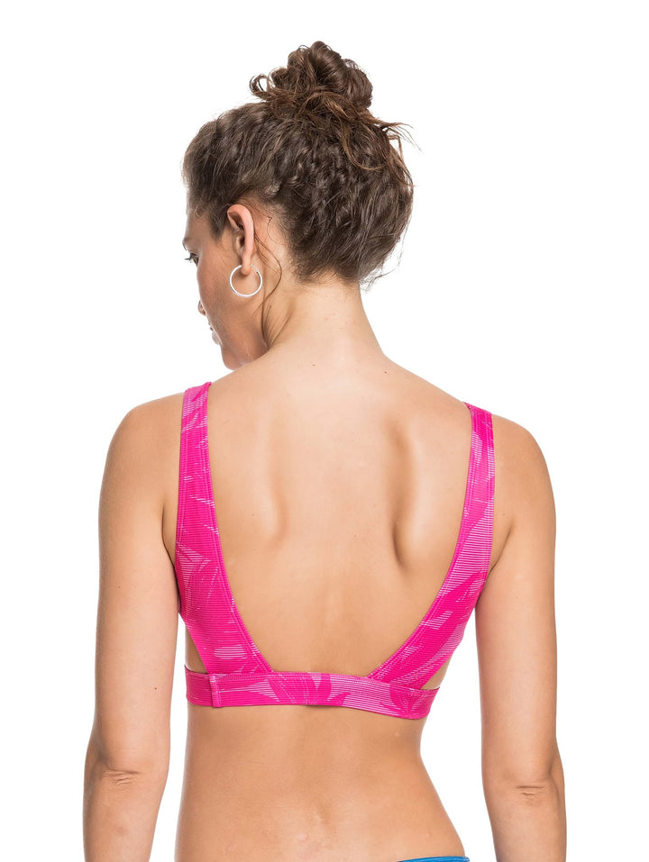 Mujer vistiendo un bralette deportivo Roxy en color rosa con estampado floral sutil.