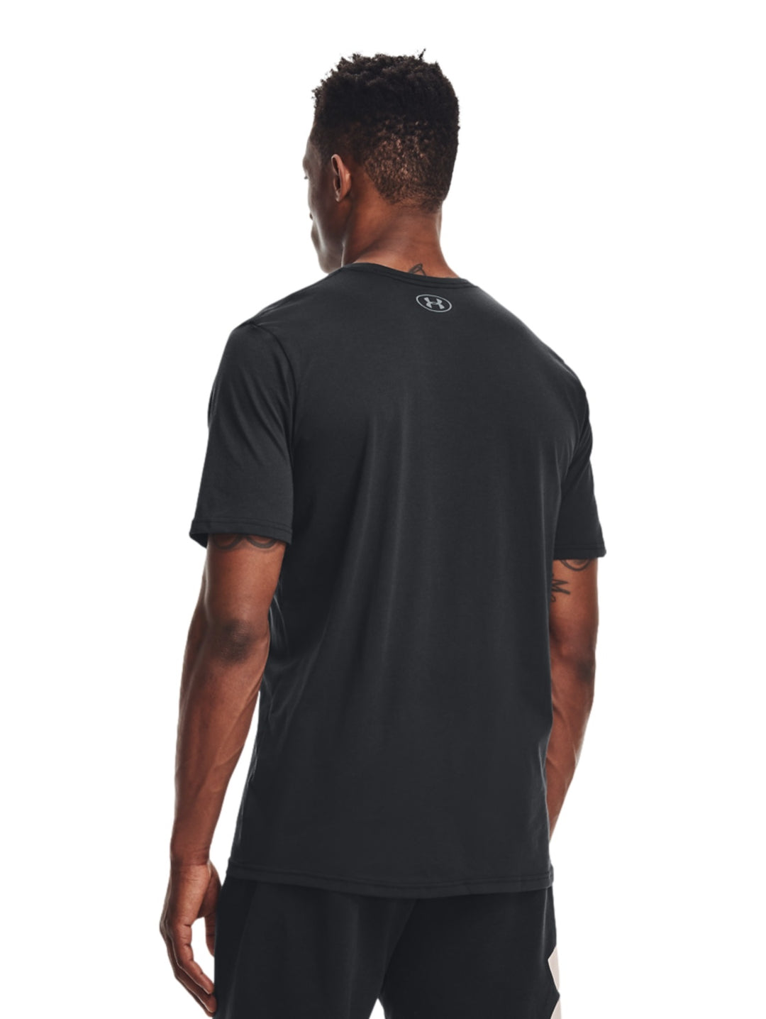 Hombre vistiendo camiseta deportiva negra de manga corta con logotipo blanco de Under Armour en el pecho.
