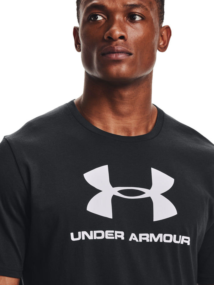 Hombre vistiendo camiseta deportiva negra de manga corta con logotipo blanco de Under Armour en el pecho.