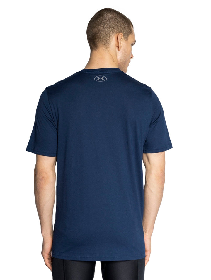 Hombre vistiendo playera deportiva Under Armour de color azul marino con logotipo blanco en el pecho.