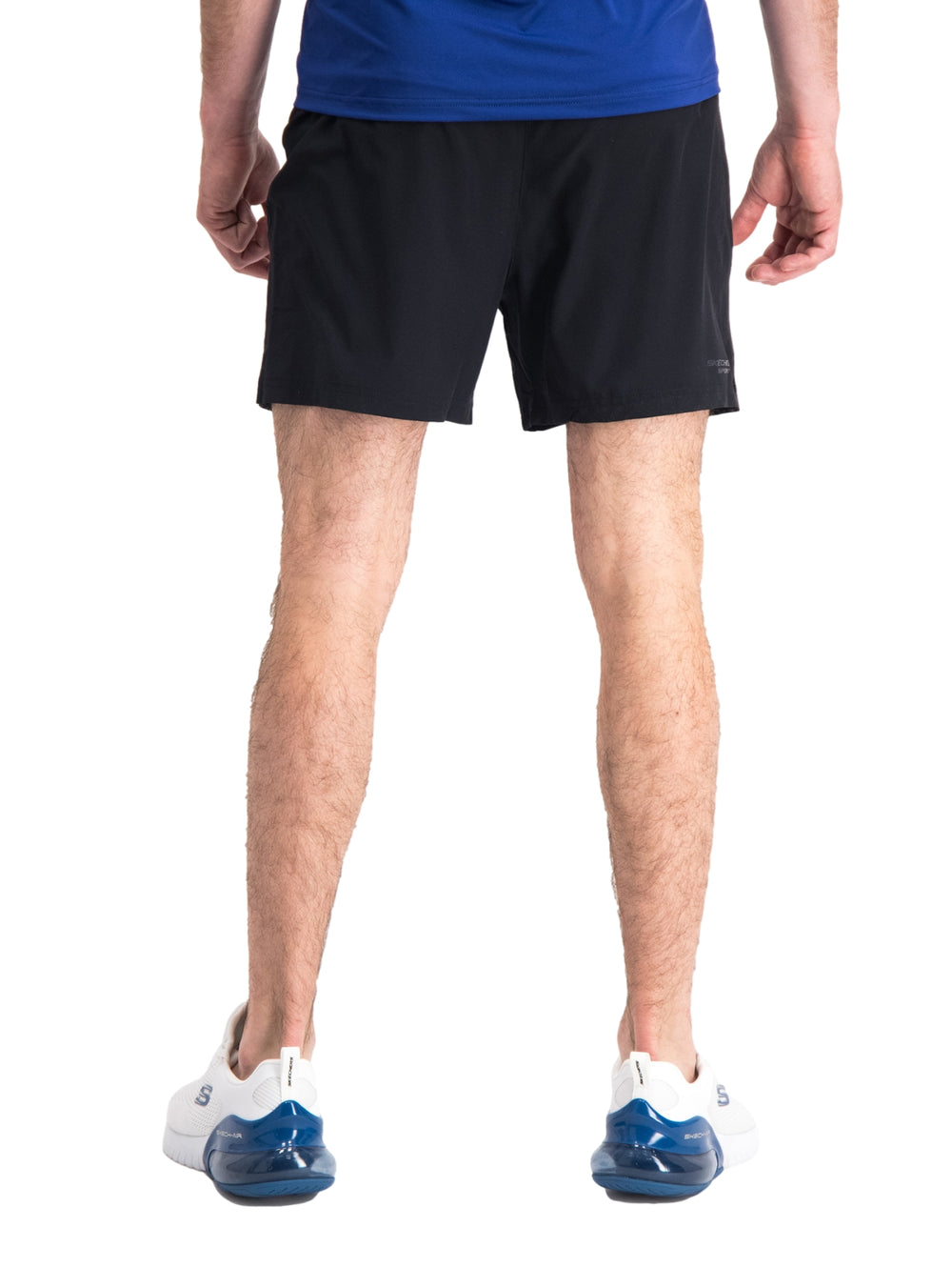 Hombre vistiendo short deportivo color negro de la marca Skechers con camiseta azul y tenis blancos.