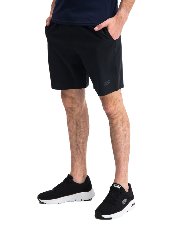 Hombre vistiendo short deportivo color negro de la marca Skechers con calzado deportivo a juego.
