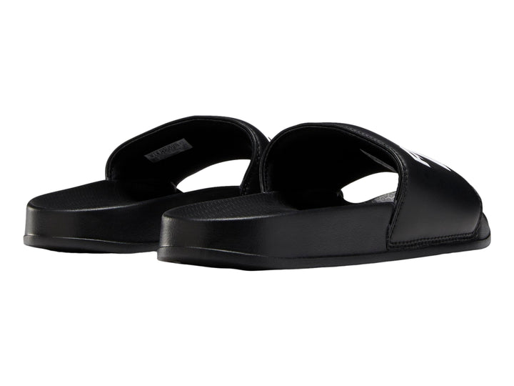Sandalia deslizable Reebok de color negro con logotipo blanco en la banda superior.