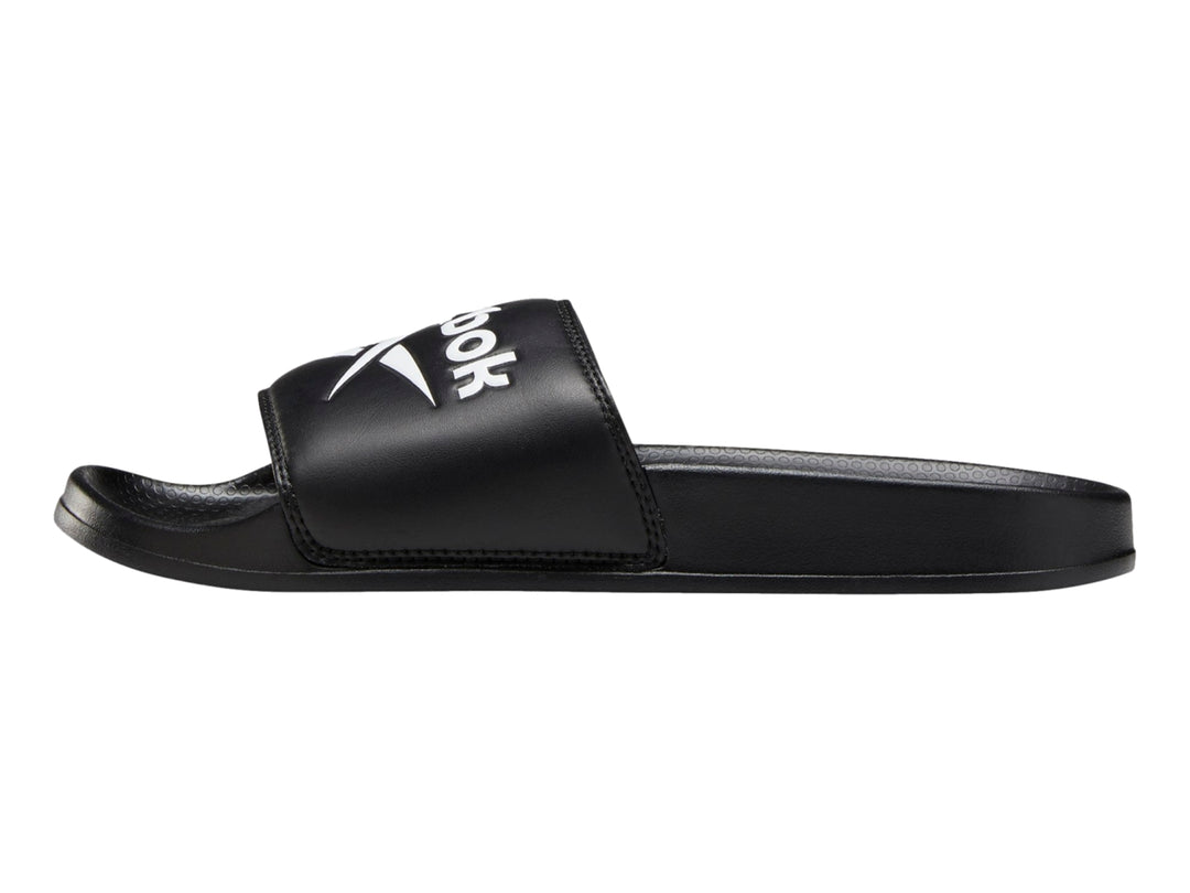 Sandalia deslizable Reebok de color negro con logotipo blanco en la banda superior.