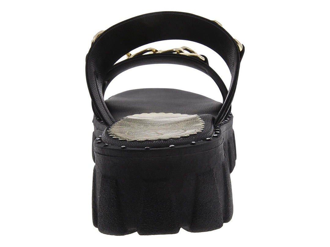 Sandalias negras de plataforma con tiras decoradas con cadenas doradas.