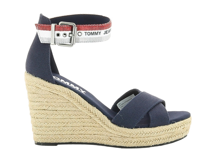 Sandalia de cuña azul con plataforma de esparto y correa al tobillo con detalles en rojo y blanco.