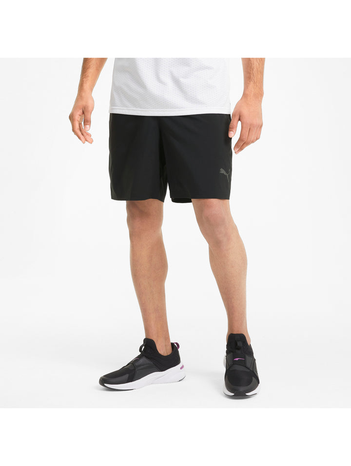 Hombre vistiendo shorts deportivos PUMA de color negro y camiseta blanca.