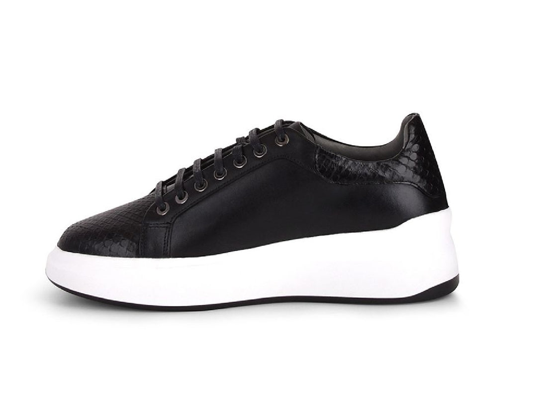 Tenis negros de cuero con textura de pitón y suela blanca ancha para mujer.