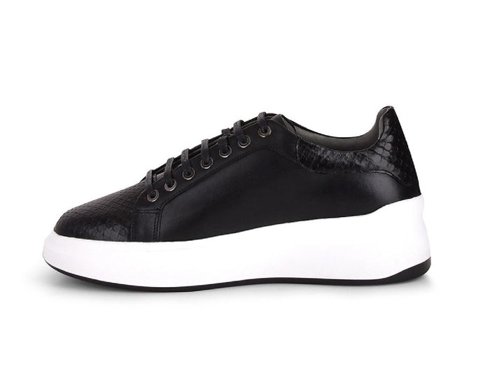 Tenis negros de cuero con textura de pitón y suela blanca ancha para mujer.
