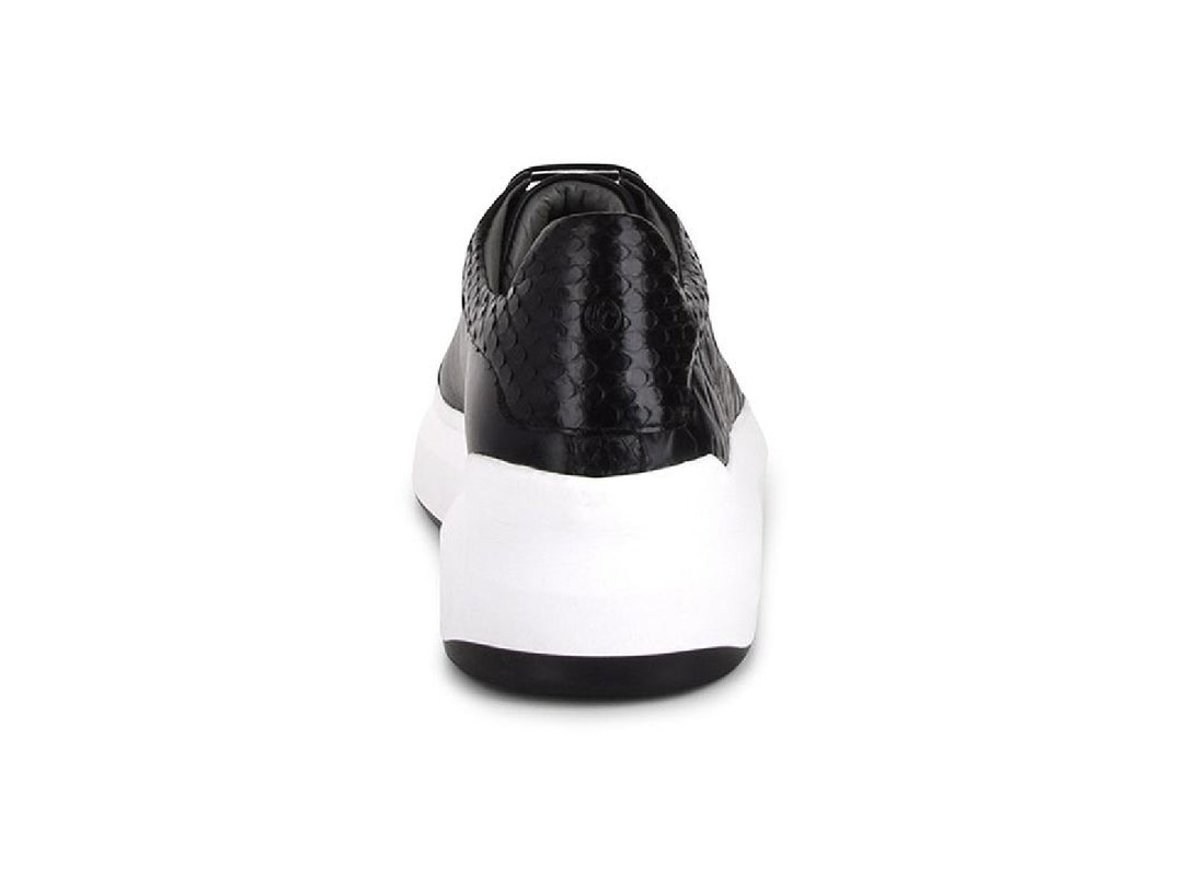 Tenis negros de cuero con textura de pitón y suela blanca ancha para mujer.