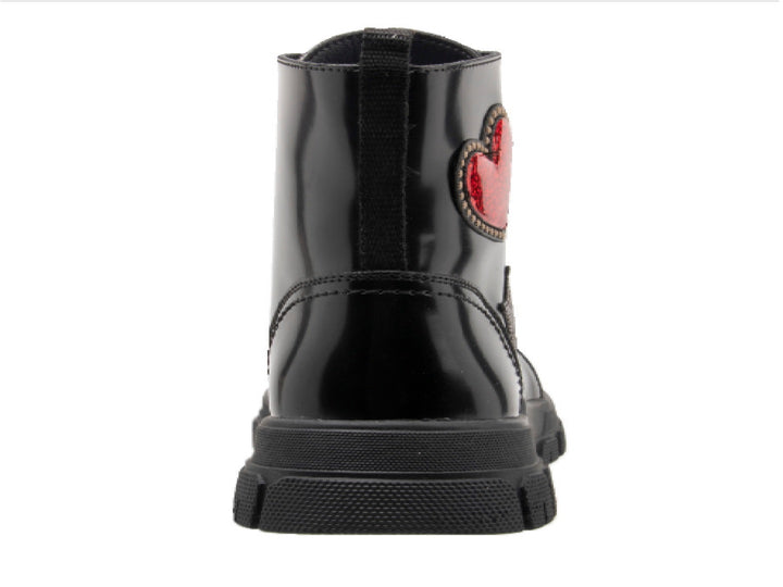 Bota infantil color negro brillante con decoraciones de corazón rojo y estrella plateada.