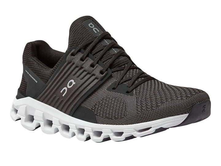 Tenis deportivos On Cloud color negro y gris con suela blanca estructurada.