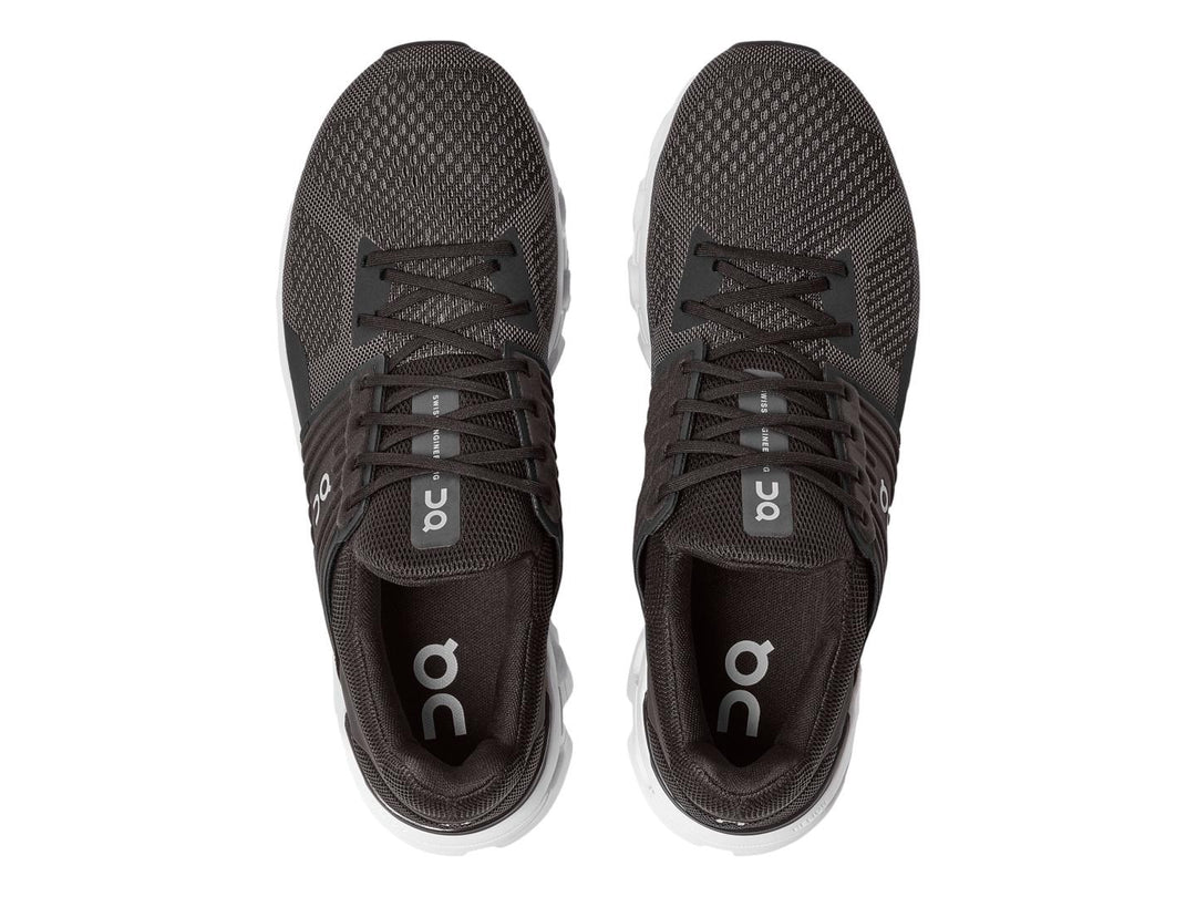 Tenis deportivos On Cloud color negro y gris con suela blanca estructurada.