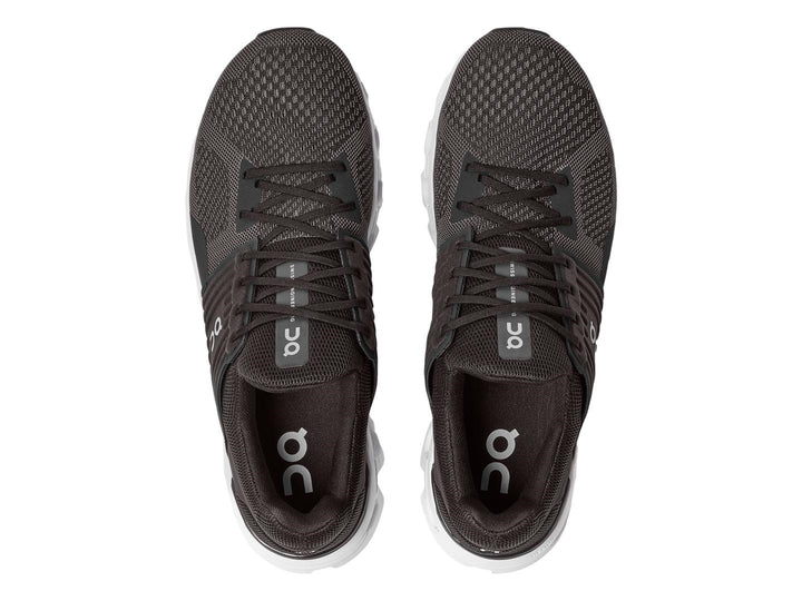 Tenis deportivos On Cloud color negro y gris con suela blanca estructurada.