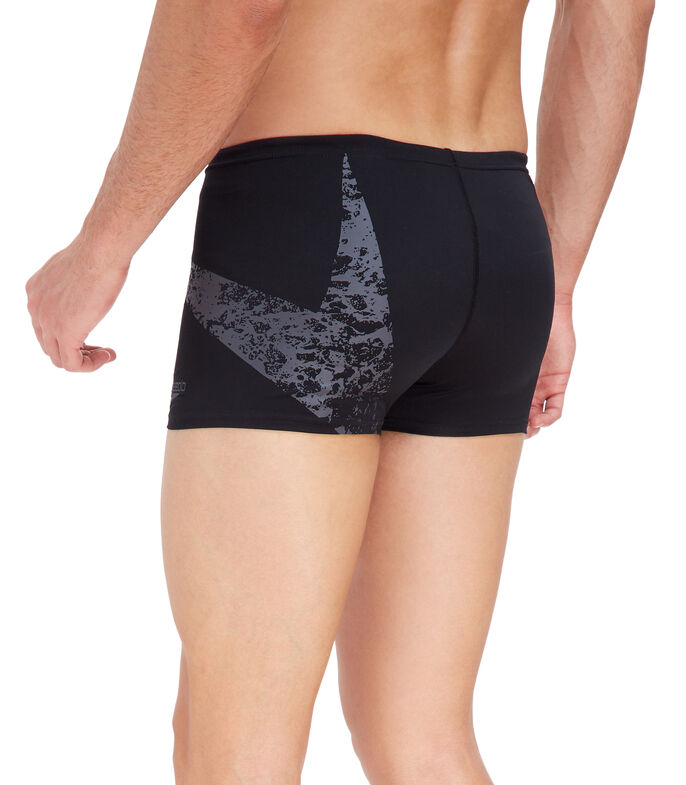 Hombre vistiendo shorts de natación Speedo color negro con detalle gráfico en gris en el lateral.