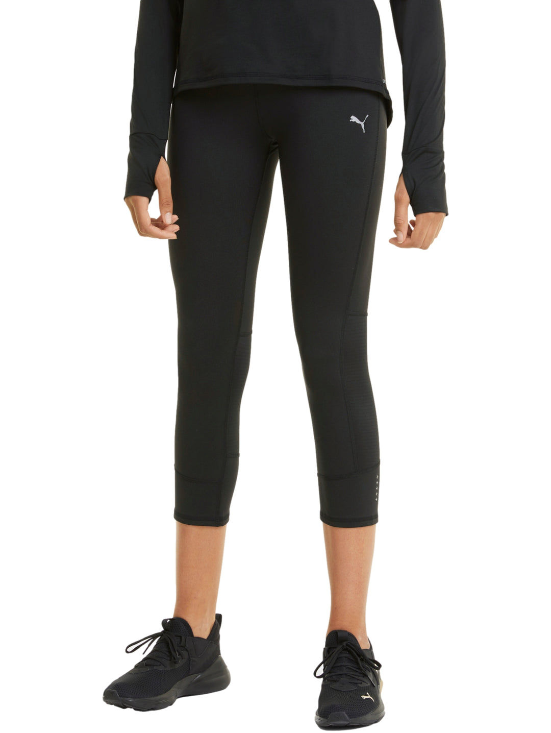 Mujer vistiendo mallas deportivas PUMA de color negro, longitud 3/4, ajustadas al cuerpo.