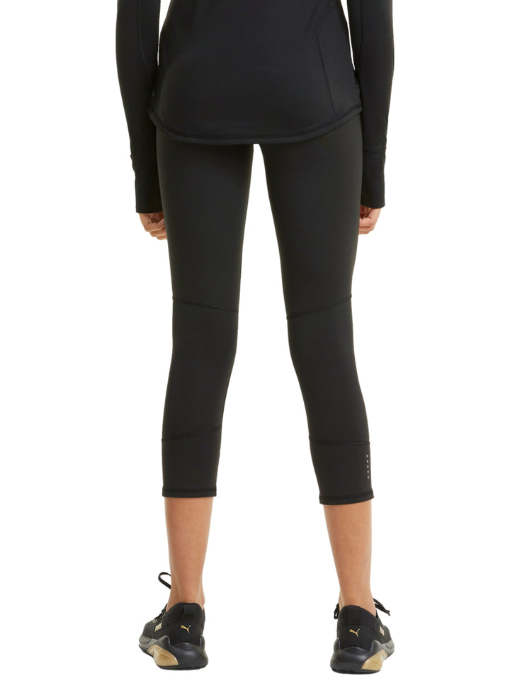 Mujer vistiendo mallas deportivas PUMA de color negro, longitud 3/4, ajustadas al cuerpo.