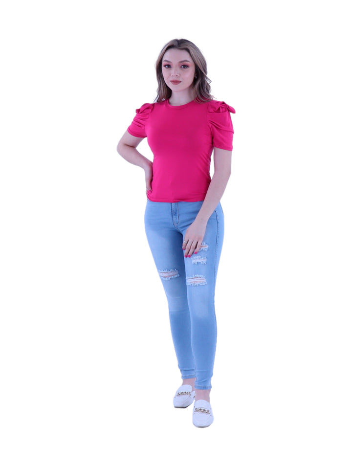 Mujer vistiendo blusa color fucsia de manga corta con detalles fruncidos en los hombros.