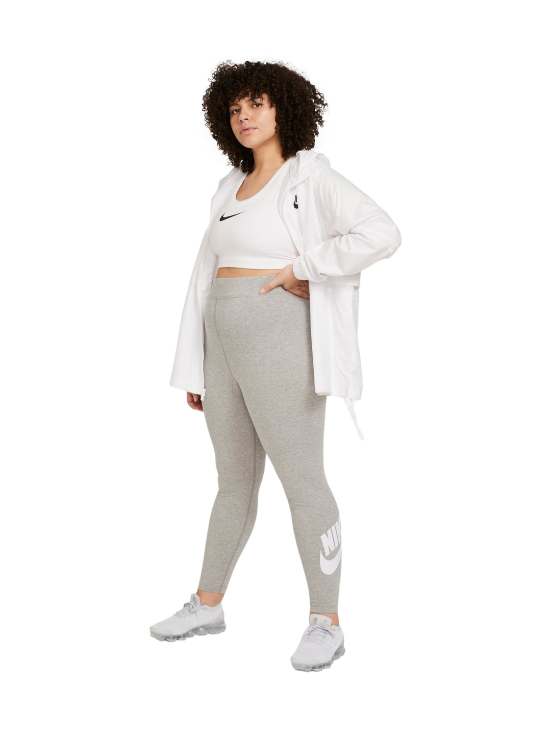 Mujer vistiendo mallas deportivas Nike de color gris jaspeado con logotipo blanco en la pierna.