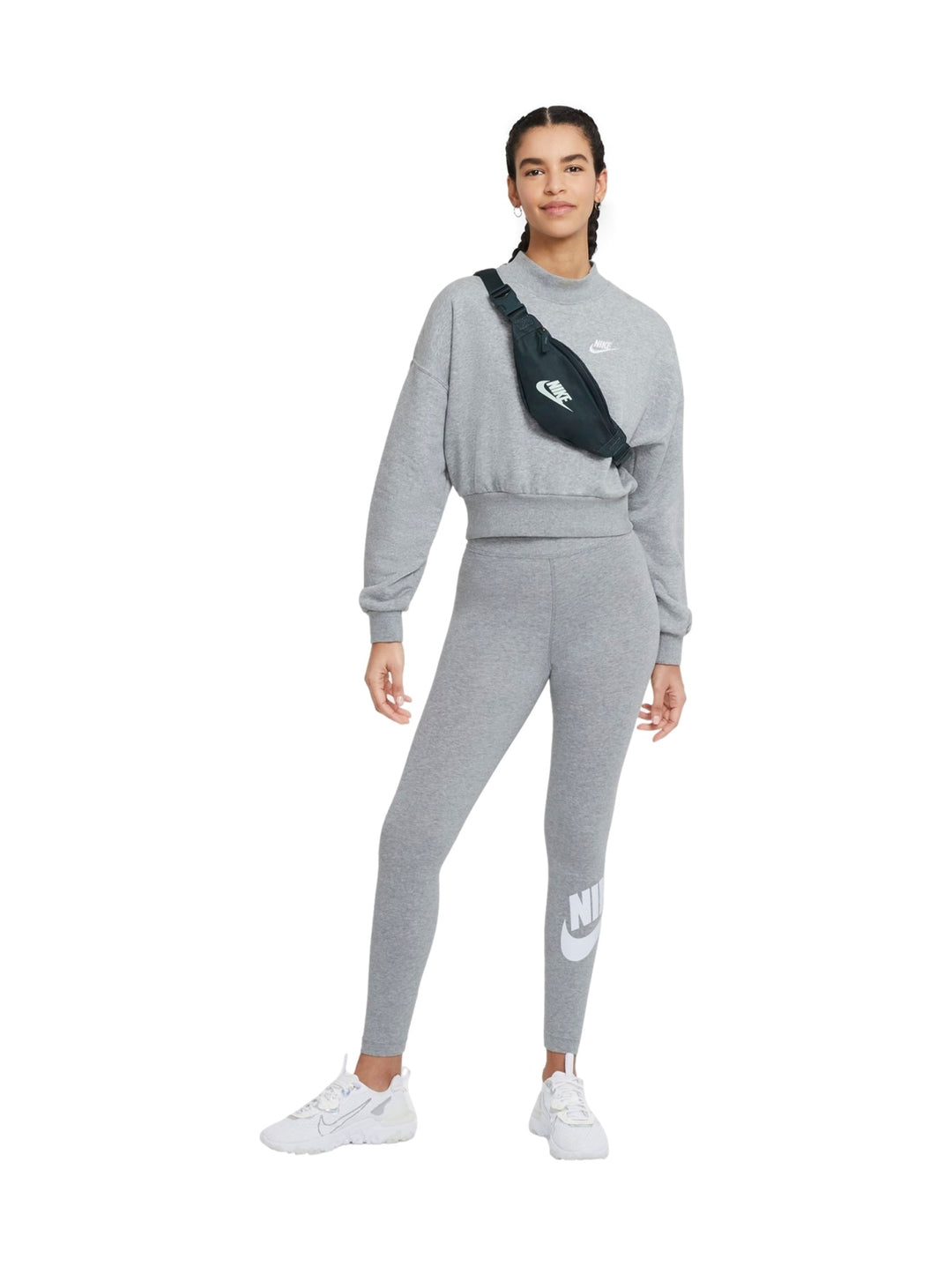 Mujer vistiendo mallas deportivas Nike de color gris jaspeado con logotipo blanco en la pierna.