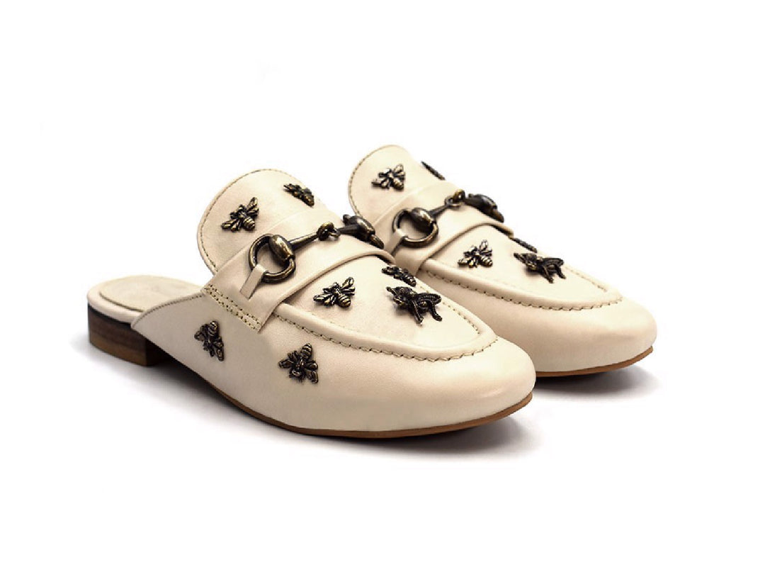 Zuecos color nude para mujer con detalles metálicos decorativos y tacón bajo marrón.