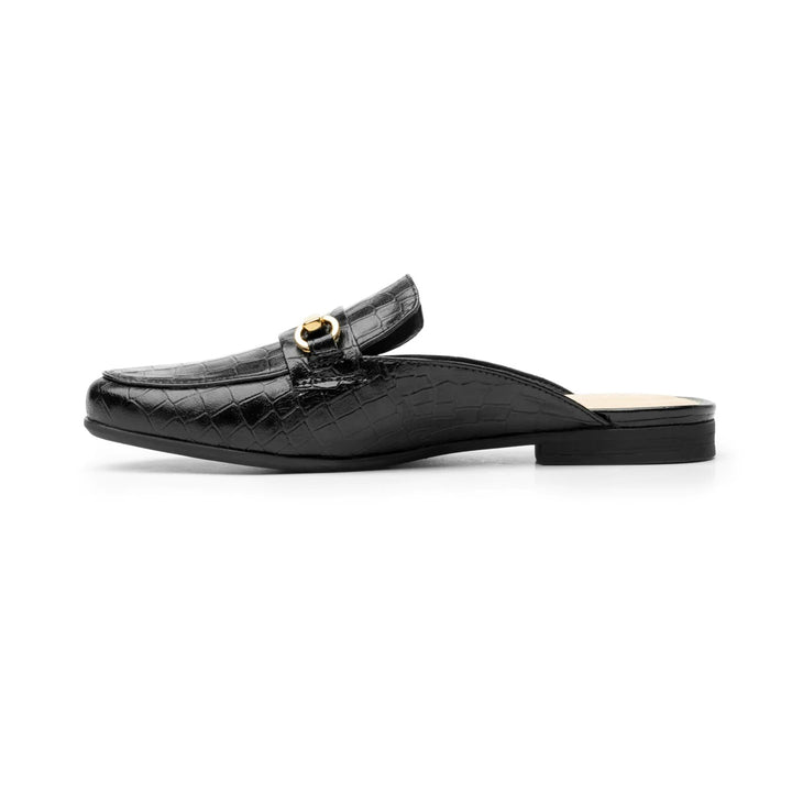 Zapato tipo mocasín destalonado color negro con textura de cocodrilo y hebilla dorada decorativa.