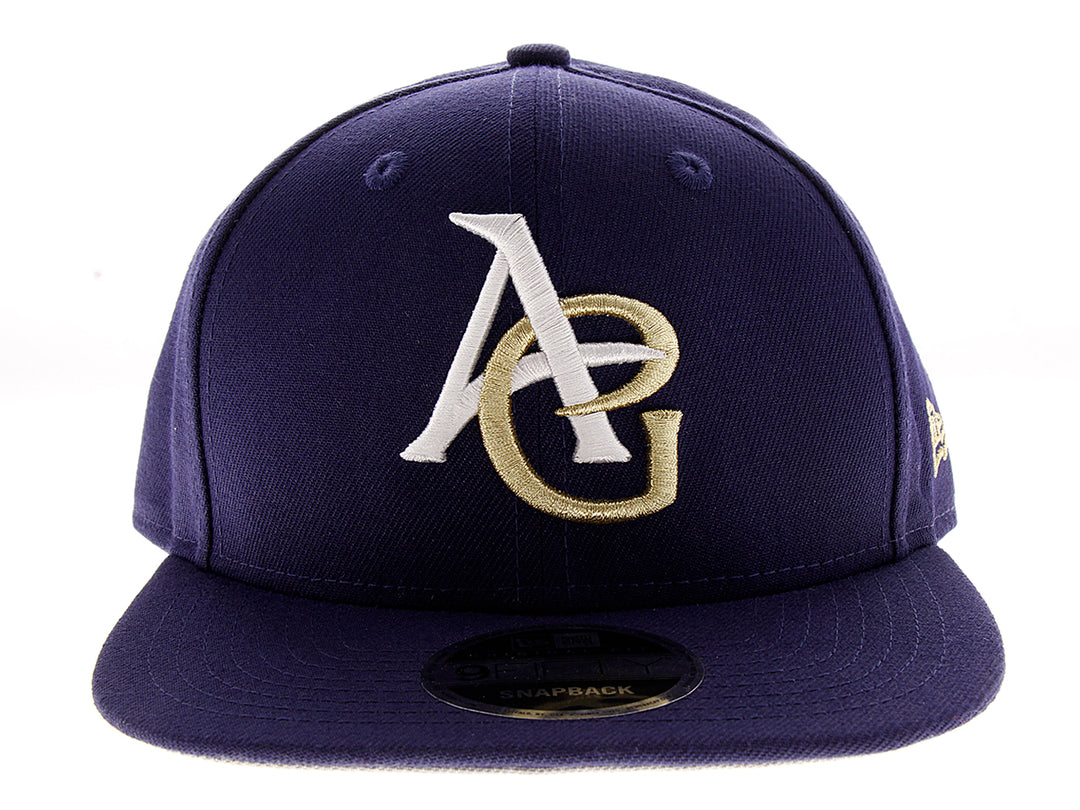 Gorra de béisbol New Era color azul marino con letras A y G bordadas en blanco y dorado.