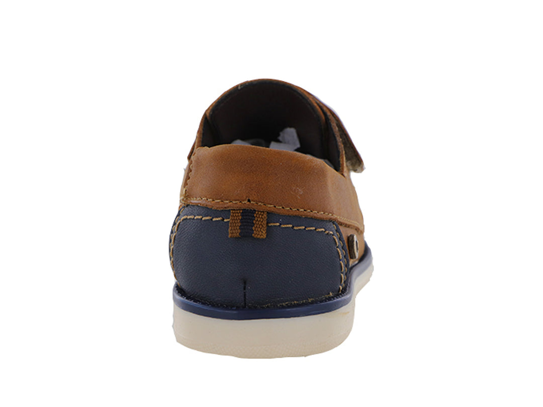 Zapatos tipo mocasín color tan para niño con correa ajustable y suela blanca con detalle azul.