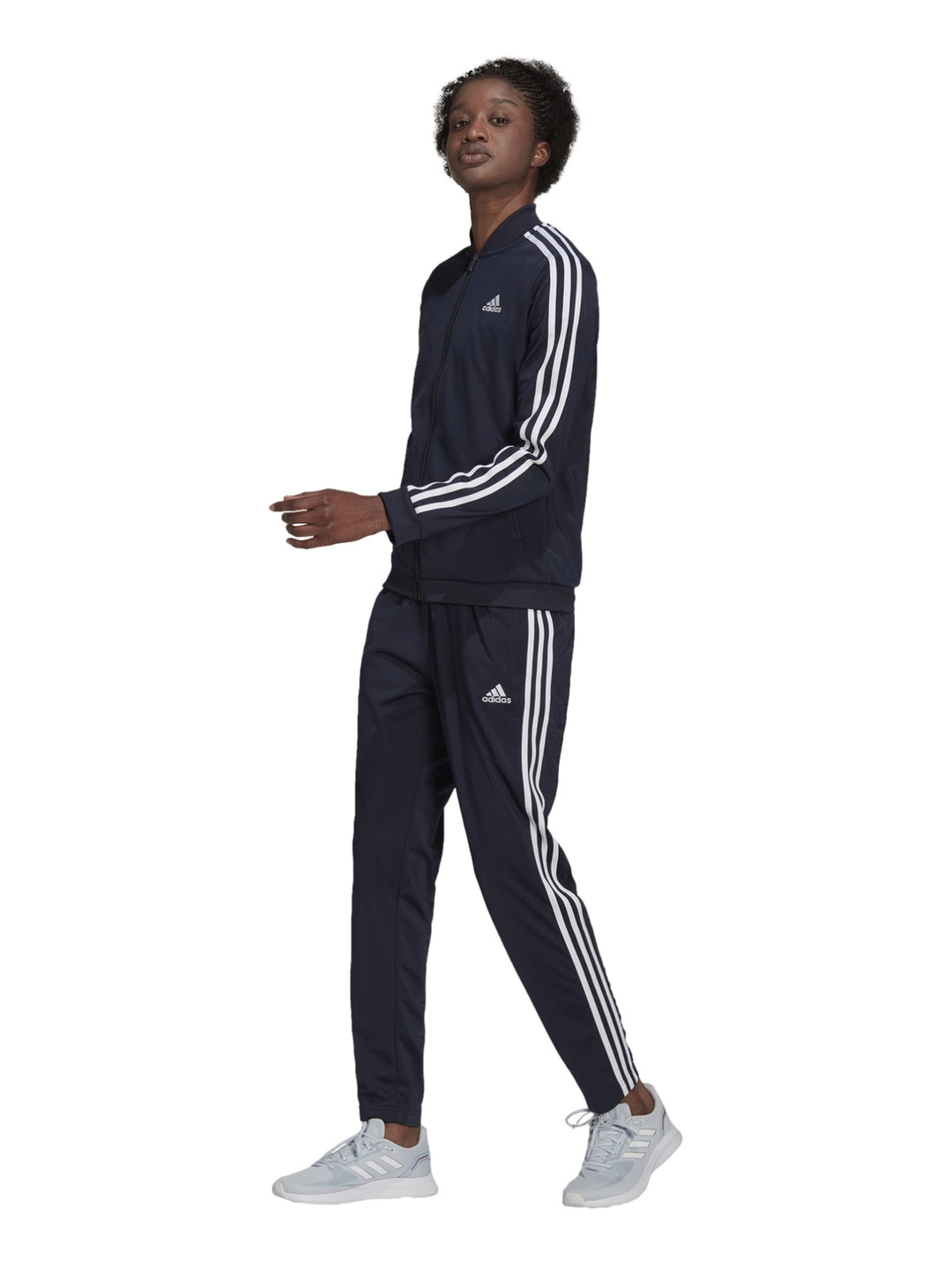 Mujer vistiendo conjunto deportivo Adidas azul marino oscuro con rayas blancas laterales.