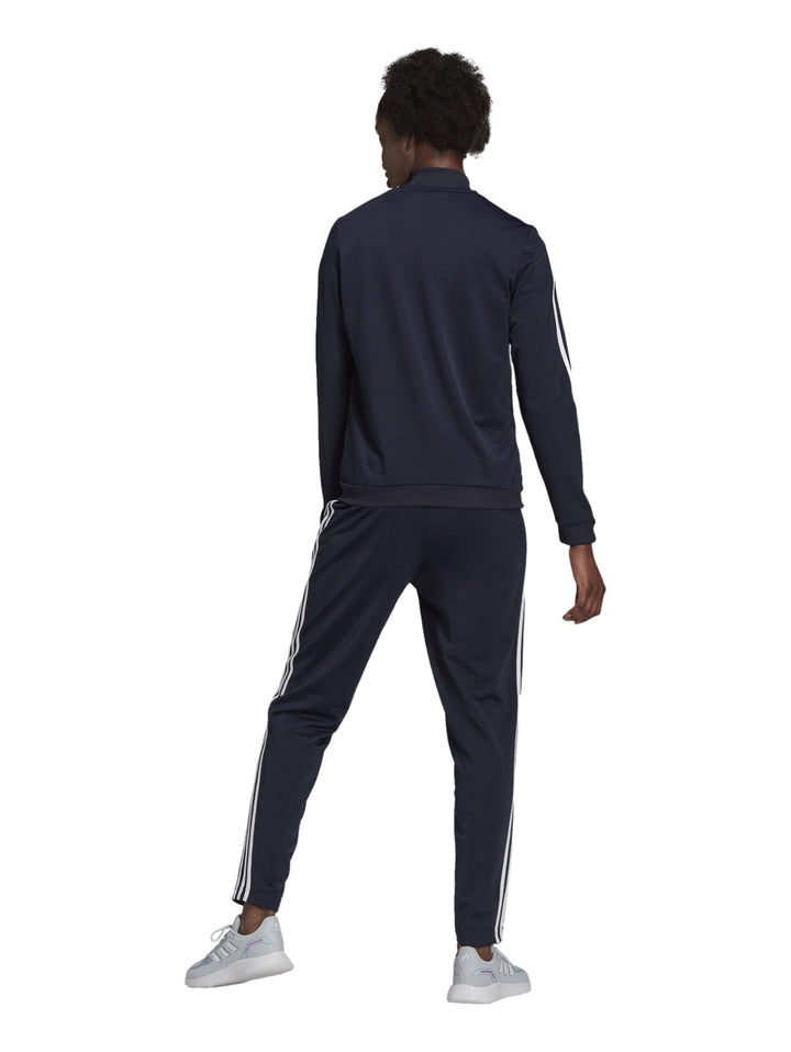 Mujer vistiendo conjunto deportivo Adidas azul marino oscuro con rayas blancas laterales.