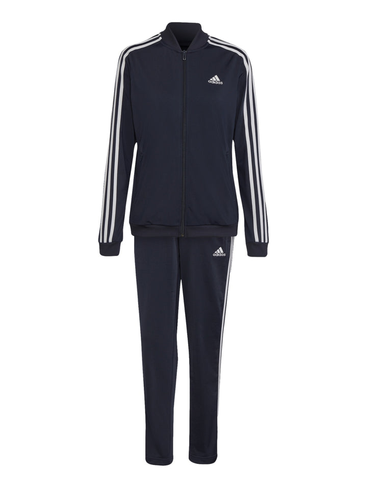 Mujer vistiendo conjunto deportivo Adidas azul marino oscuro con rayas blancas laterales.