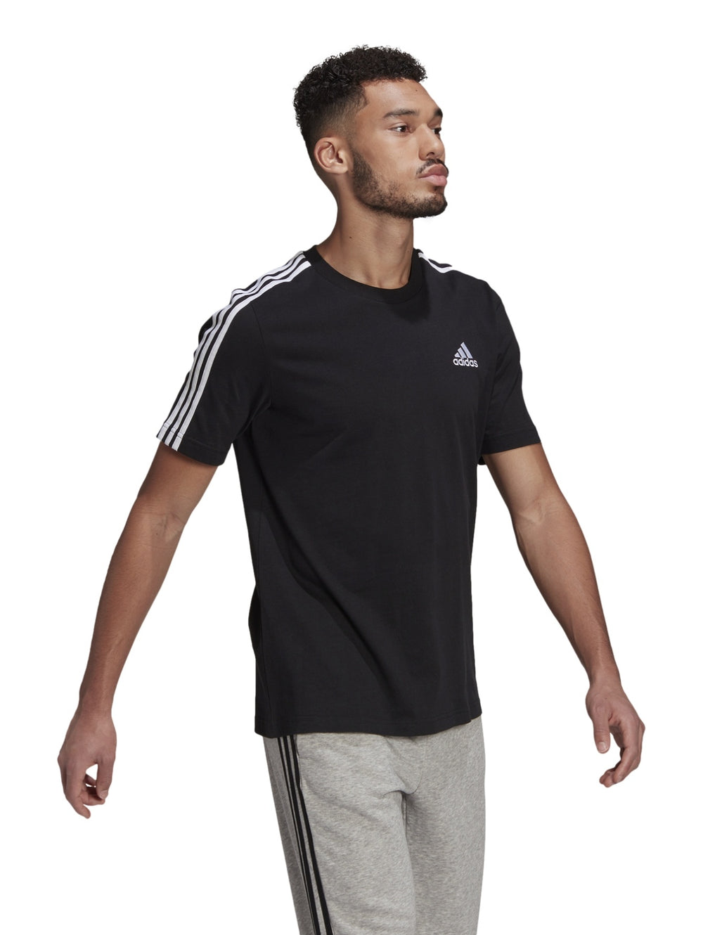 Hombre vistiendo playera deportiva Adidas color negro con tres franjas blancas en los hombros.