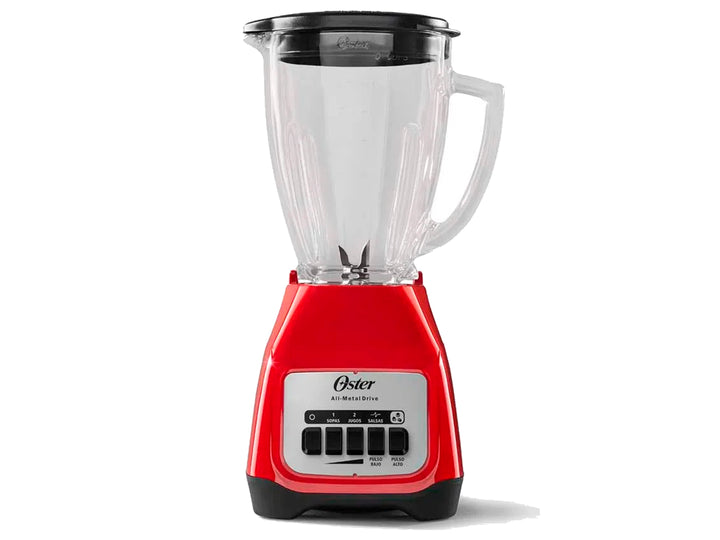 Licuadora Oster de color rojo con vaso de vidrio transparente lleno de arándanos y hielo.