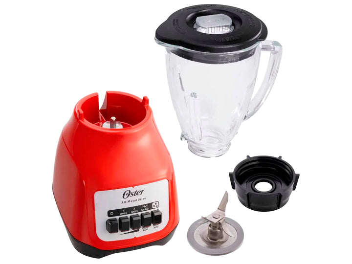 Licuadora Oster de color rojo con vaso de vidrio transparente lleno de arándanos y hielo.