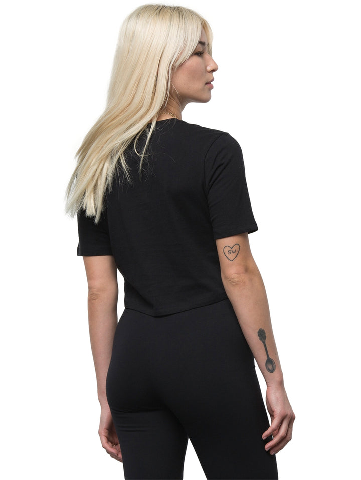 Mujer vistiendo una camiseta crop top color negro de marca Vans con cuello redondo y manga corta.