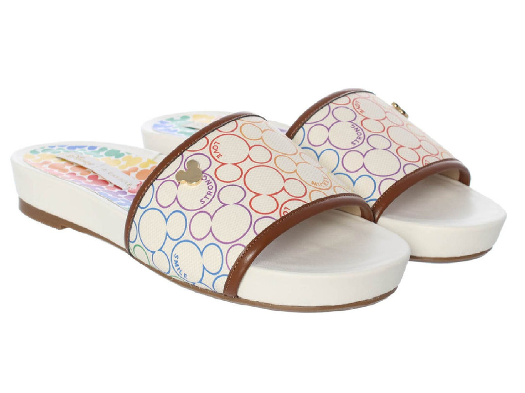 Sandalias slide color marfil con estampado multicolor de Mickey Mouse y ribete marrón.