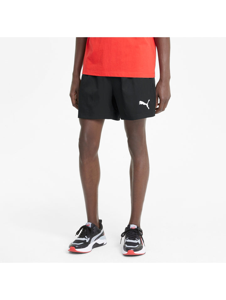 Hombre vistiendo shorts deportivos PUMA de color negro con logo blanco lateral.