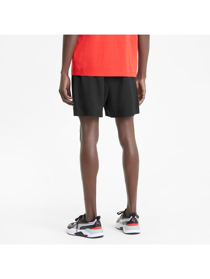 Hombre vistiendo shorts deportivos PUMA de color negro con logo blanco lateral.