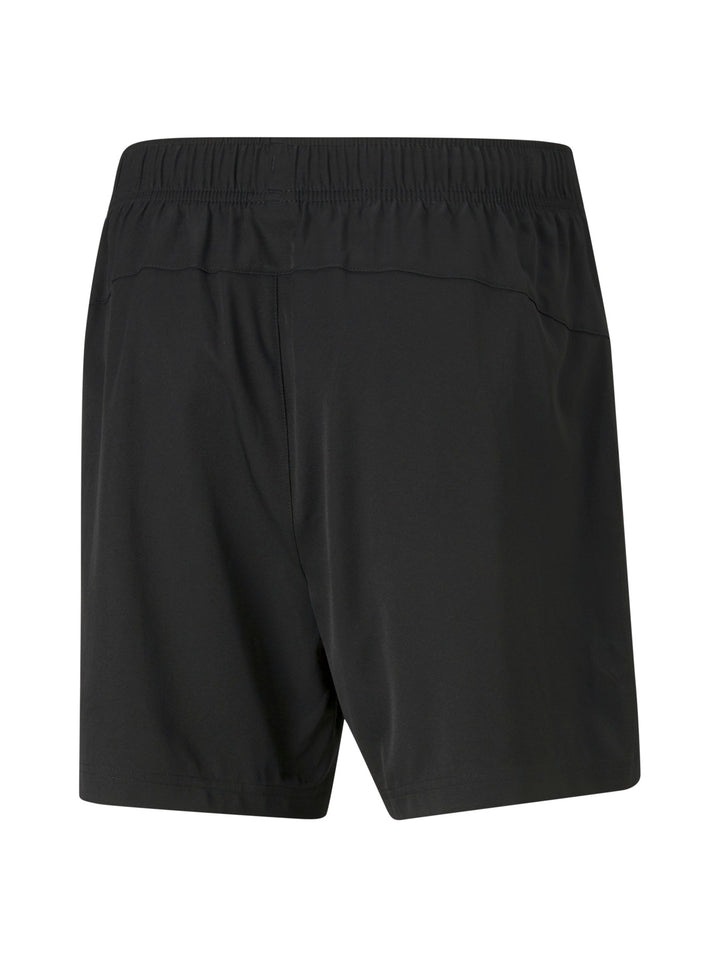 Hombre vistiendo shorts deportivos PUMA de color negro con logo blanco lateral.