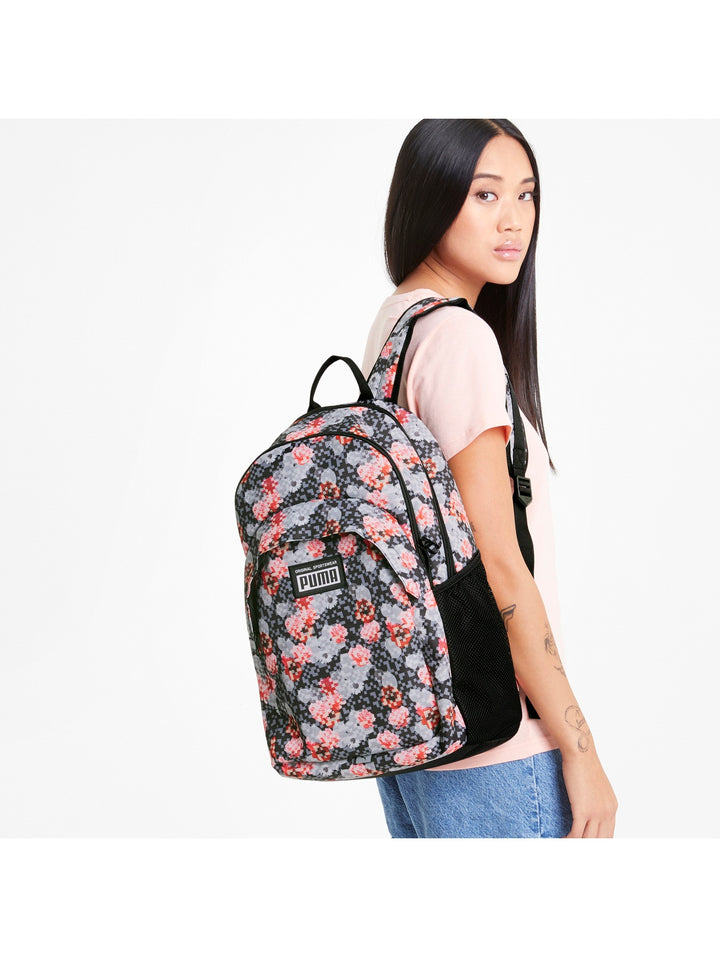 Mochila PUMA Academy con estampado floral en colores gris y rojo sobre fondo oscuro.